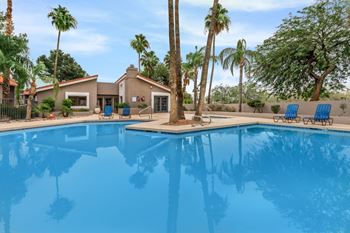 A pool in front of a house with palm trees.